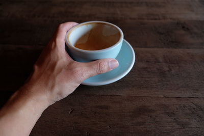 Cropped image of person holding coffee cup on table