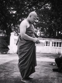 Monk reading book while standing outdoors