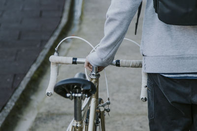 Young man walking backwards with bicycle in town, transportation and sport