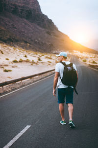 Traveler with backpack walks in the center of an epic winding road. sao vicente cape verde