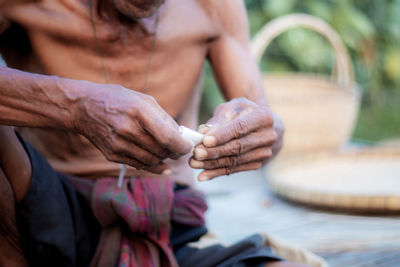 Midsection of man holding hands sitting outdoors