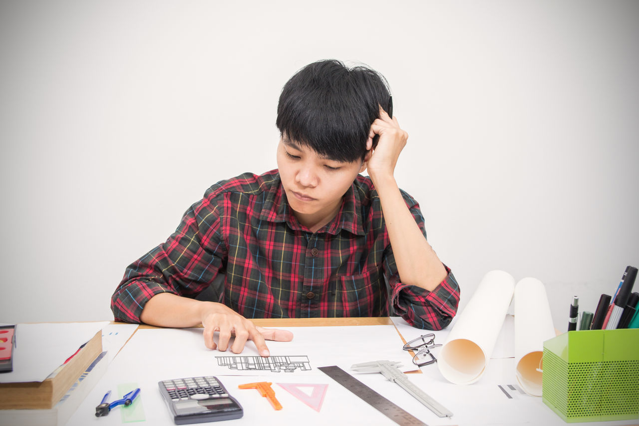 PORTRAIT OF MAN USING PHONE WHILE SITTING ON TABLE