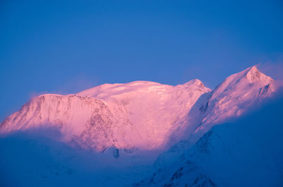 Scenic view of snowcapped mountains against blue sky