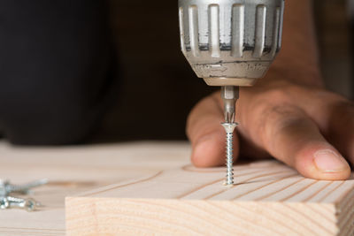 Cropped hand of man drilling wood at home