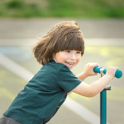 Cute boy playing with push scooter outdoors