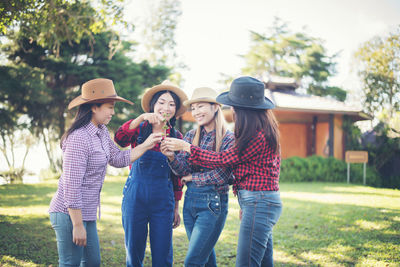 Happy female friends looking at buds while standing at park