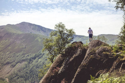 Man standing on rock against sky