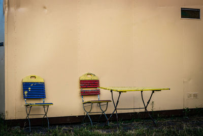 Empty chairs and table against wall