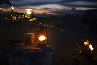 Lit tea light candles on table against sky at sunset