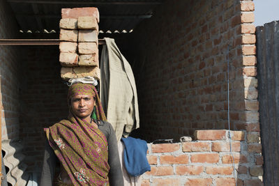 Portrait of woman wearing sari standing carrying bricks on head