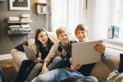 Male and female friends using laptop while sitting at sofa