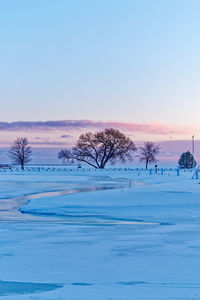 Scenic view of snow field against clear sky during sunset