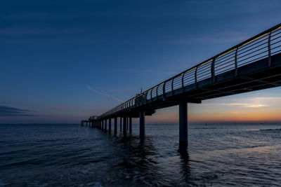 Bridge over calm sea at sunset