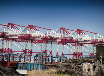 Cranes at pier against clear sky