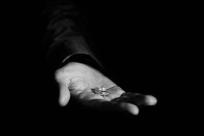 Cropped hand of woman holding cigarette against black background