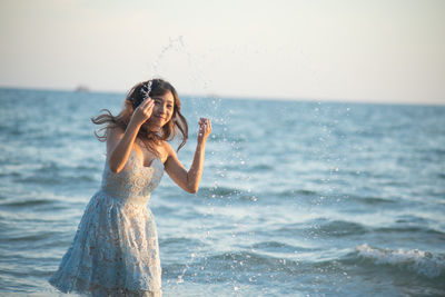 Woman splashing water in sea against sky