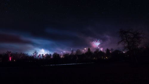 Silhouette trees on field against sky at night