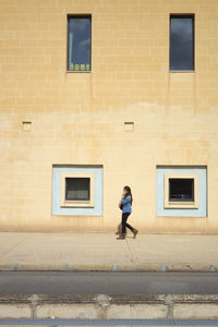 Woman walking on brick wall