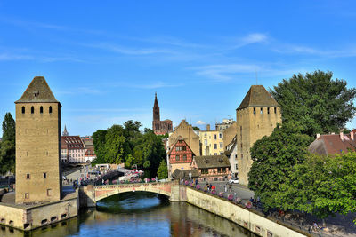 Arch bridge over river amidst buildings against sky