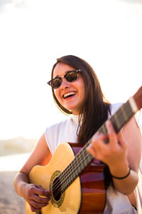 Portrait of smiling young woman playing guitar