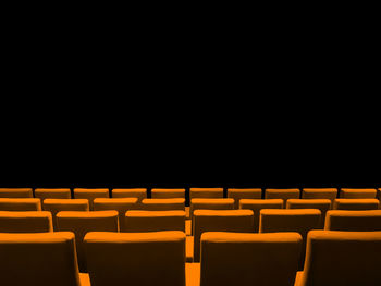 Empty chairs in row against black background