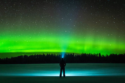 Full length rear view of silhouette man standing against sky at night with northern lights