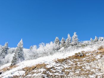 Low angle view of snowcapped mountain against clear blue sky