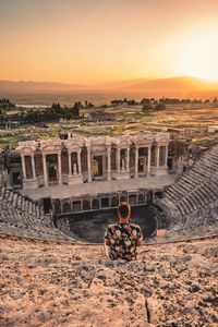 Rear view of man looking old ruins during sunset