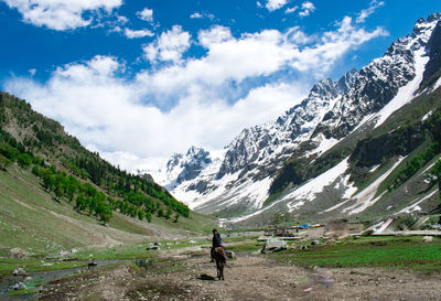 Rear view of boy walking on mountain against sky