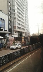 Cars on road by buildings against sky in city