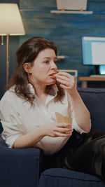 Woman eating while sitting at home