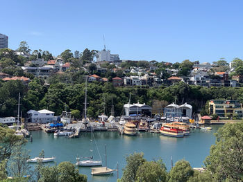 Sailboats moored on harbor by buildings against clear sky