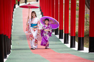 Rear view of women walking with red umbrella