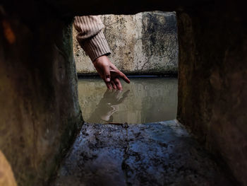 Midsection of woman with umbrella on concrete wall