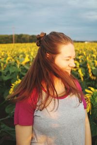 Woman with long hair standing on sunflower field