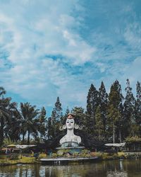 Statue by trees against sky