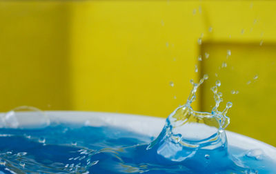 Close-up of water splashing against yellow wall