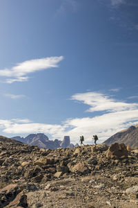 Distant view of two backpackers hiking over glacial moraine.