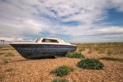 Abandoned ship on field against sky