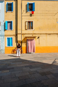 Woman walking on footpath against building