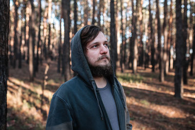 Bearded young man looking away in forest