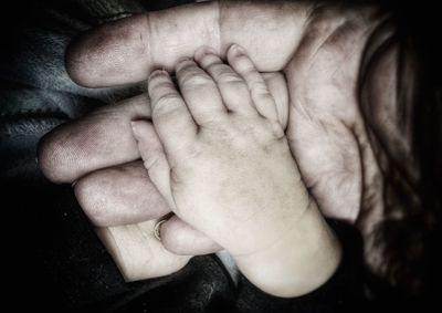 Close-up of father holding baby hand