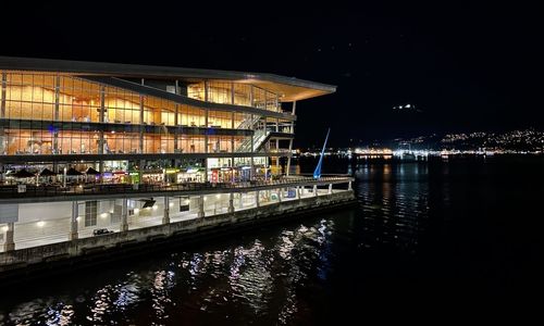 Illuminated pier over river in city at night