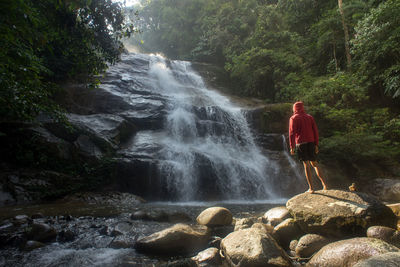 A male traveller exploring the beautiful of rainforest waterfall. 