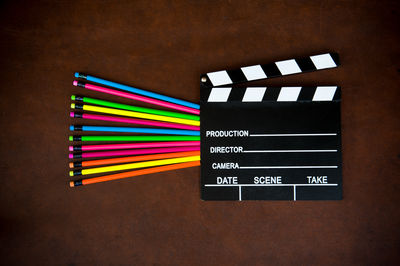 Close-up of colored pencils and clapperboard on wooden table