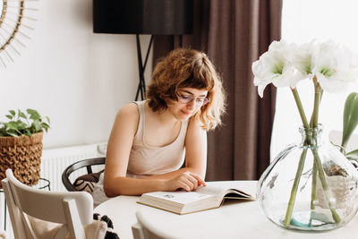 Young woman sitting on table at home