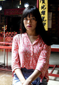 Portrait of young woman with bangs sitting in city