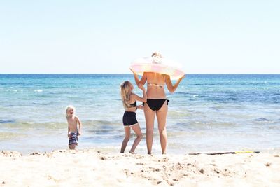 Full length of friends on beach against sky