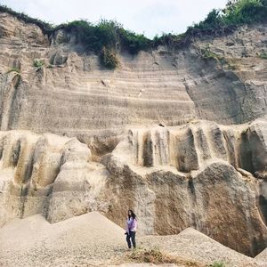 Woman standing against rock formation at pantai tebing