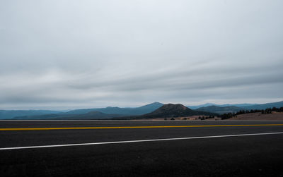 Empty road against cloudy sky